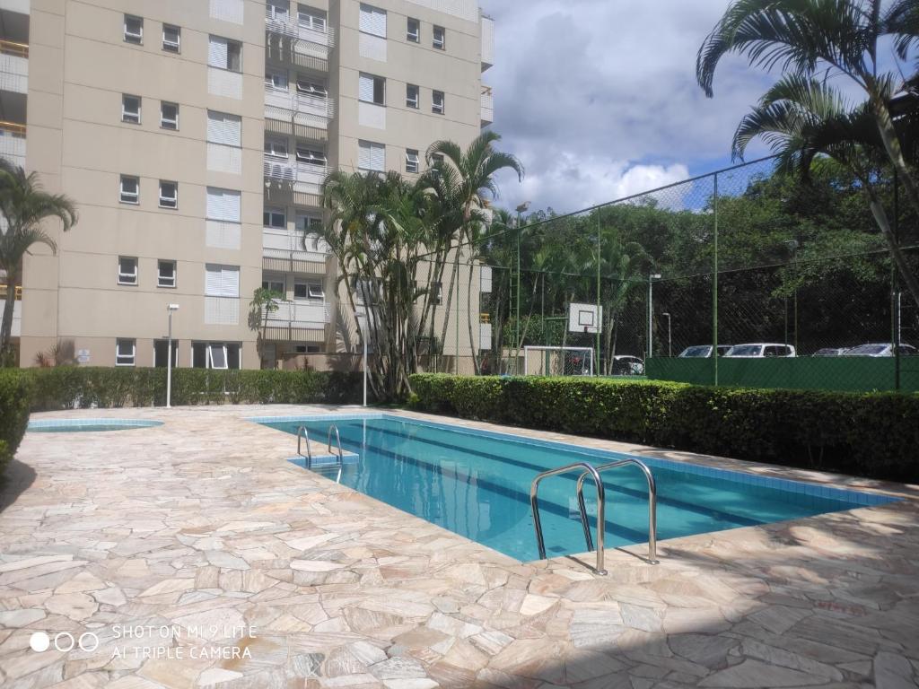 a swimming pool in front of a building at Apto 2 dormitórios à 400 m da Praia de Riviera de São Lourenço - com serviço de praia in Bertioga