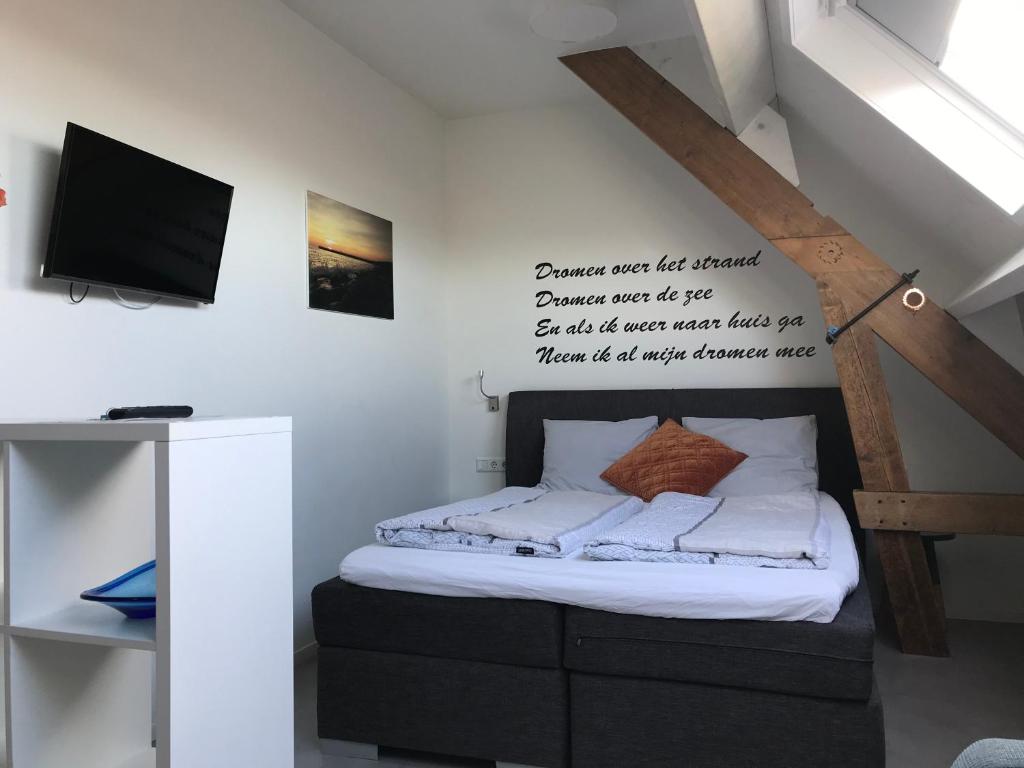 een slaapkamer met een bed met een bord aan de muur bij Hendrikhof studio nr. 4 ‘het Spant’ in Westkapelle