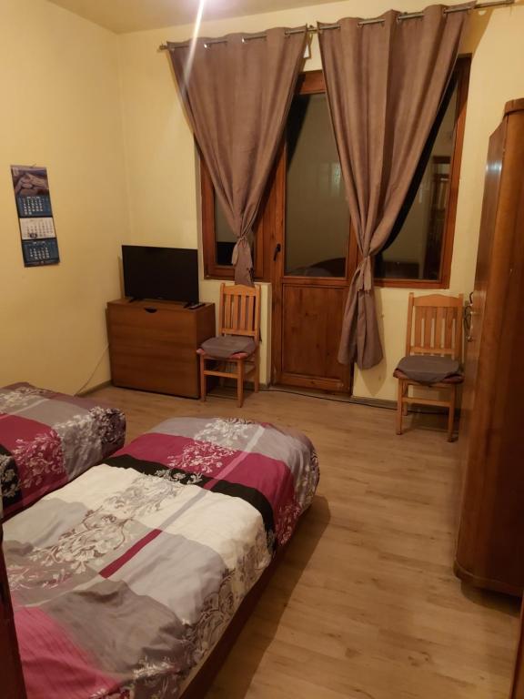 a bedroom with two beds and a tv and a window at Цар Освободител 108 in Ruse