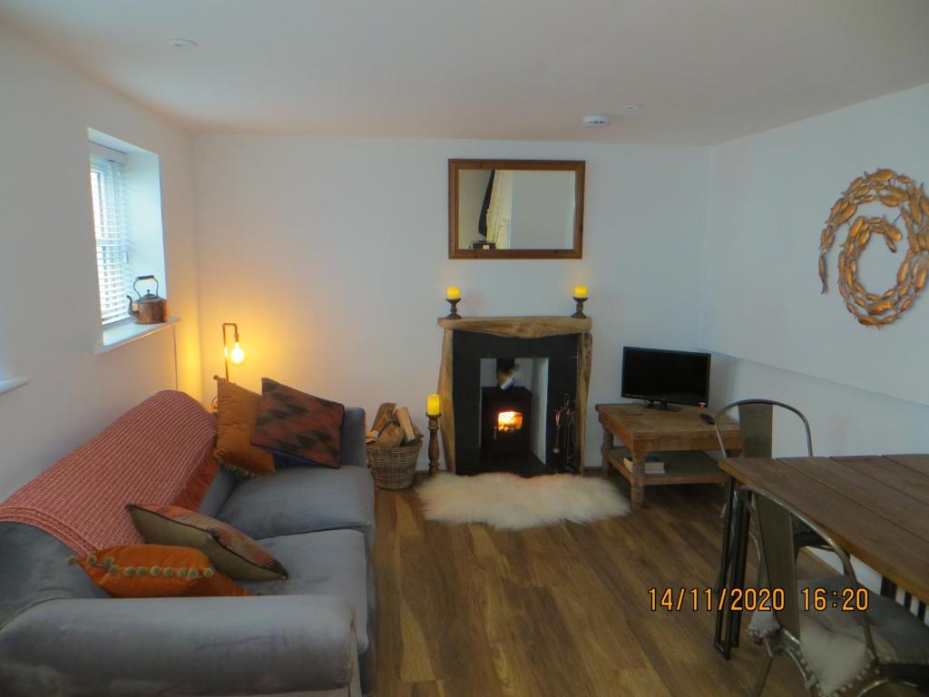 sala de estar con sofá y chimenea en Pengelly - Luxury converted Fisherman’s Net Loft, en Mousehole
