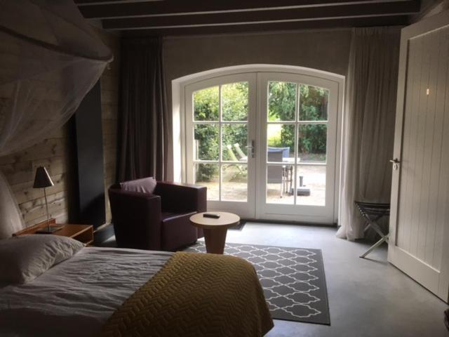 1 dormitorio con cama y ventana grande en Vakantiehuis bij Bedaf, en Uden
