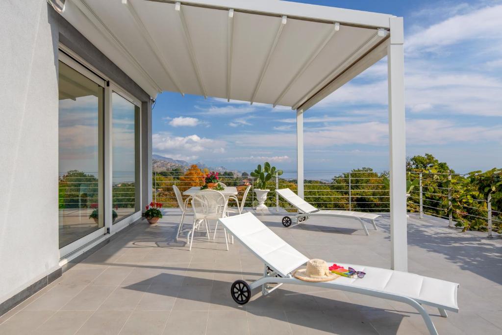 ピエディモンテ・エトネーオにあるDesign Villa in Piedimonte Etneoの白い天蓋、テーブルと椅子付きのパティオ