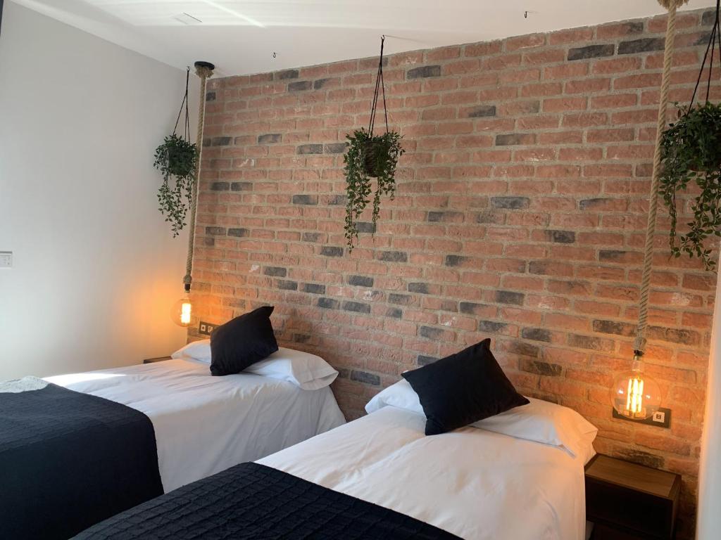 two beds in a room with a brick wall at Hotel Riojano in Humanes de Madrid