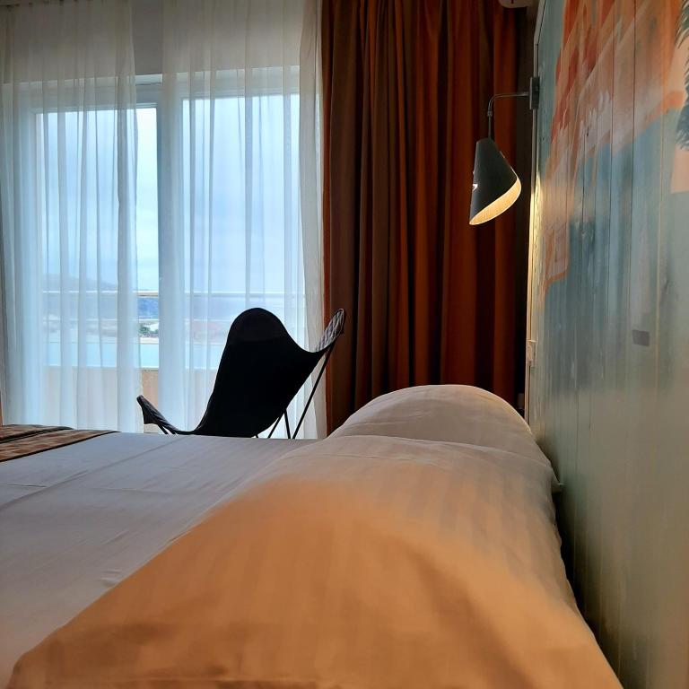 a bedroom with a bed and a chair and a window at Boutique Villa Revelin in Pag