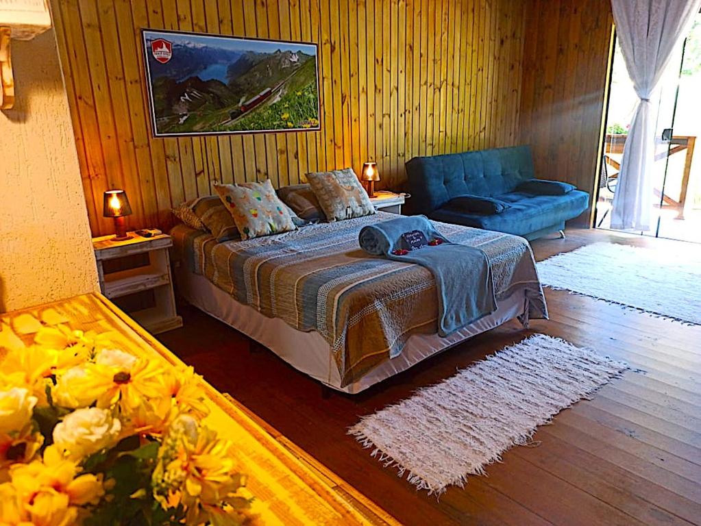 1 dormitorio con 1 cama y 1 sofá azul en Pousada Chalé Suiço Bombinhas, en Bombinhas