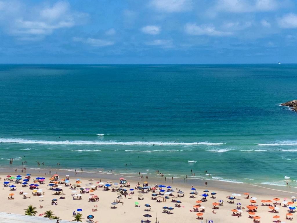 un groupe de personnes sur une plage avec parasols dans l'établissement Guarujá La Plage Pitangueiras, à Guarujá