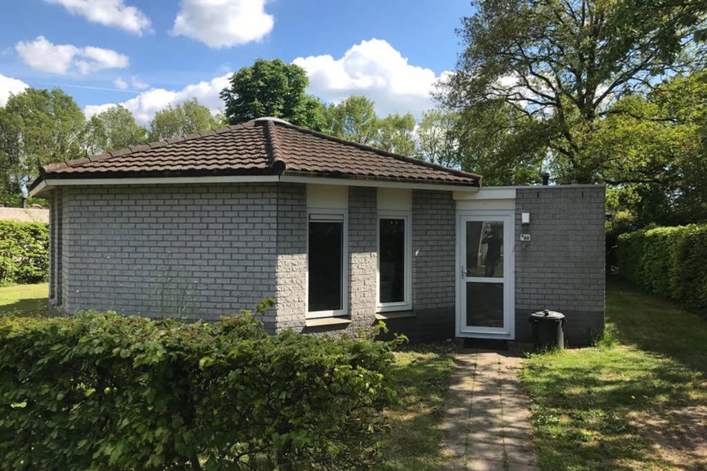 een klein bakstenen huis met een witte deur bij Rustig gelegen bungalow in mooi Havelte (Drenthe) in Havelte