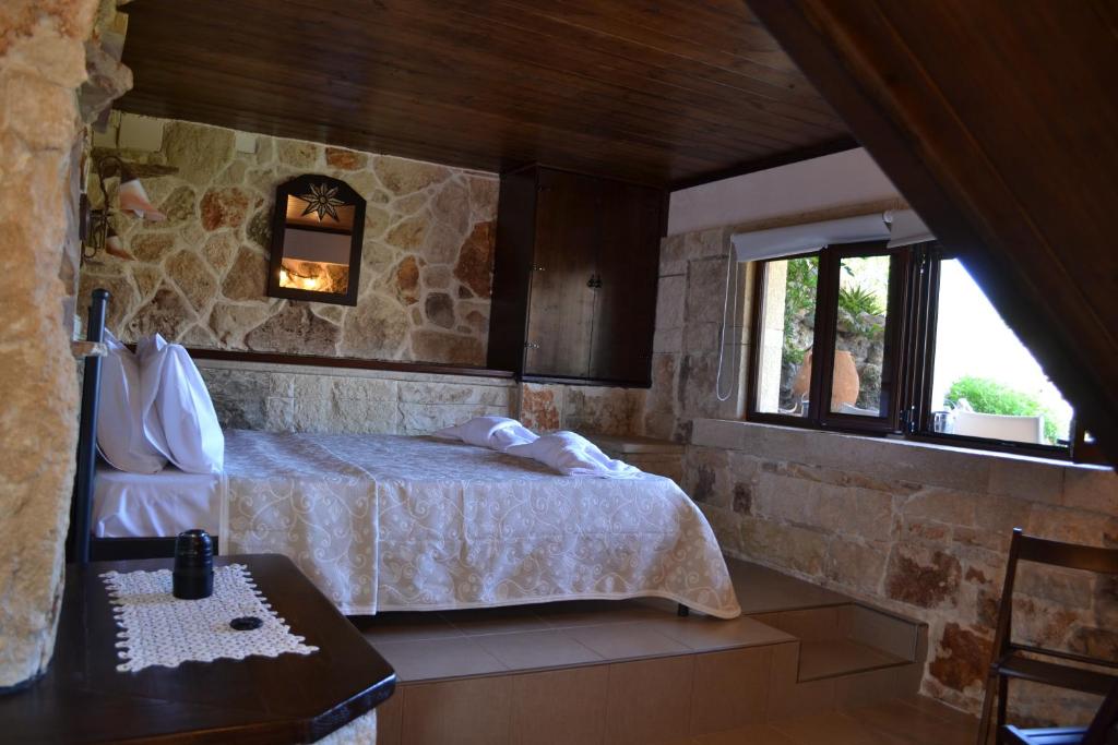 a bedroom with a bed with a stone wall at Katerina Apartments in Kato Zakros