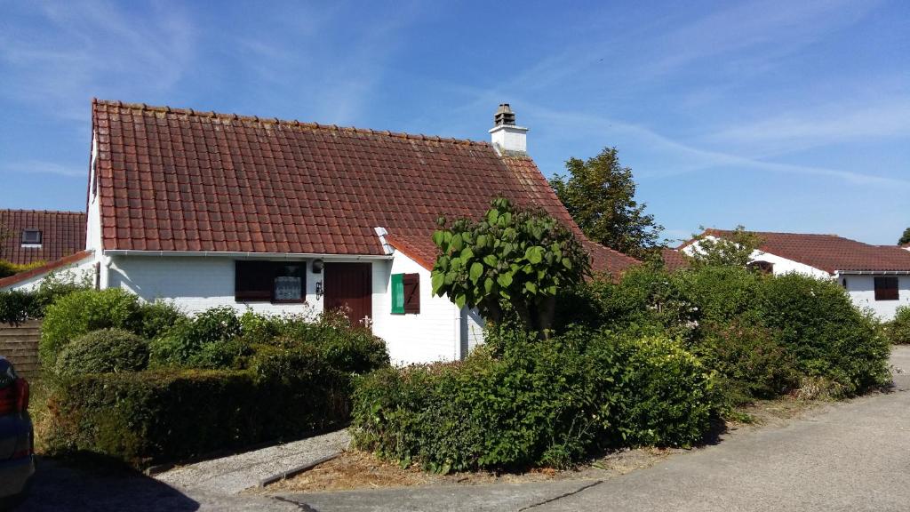 ein weißes Haus mit rotem Dach und Büschen in der Unterkunft Villa 6 pers De Haan with warm swimming pool access in De Haan