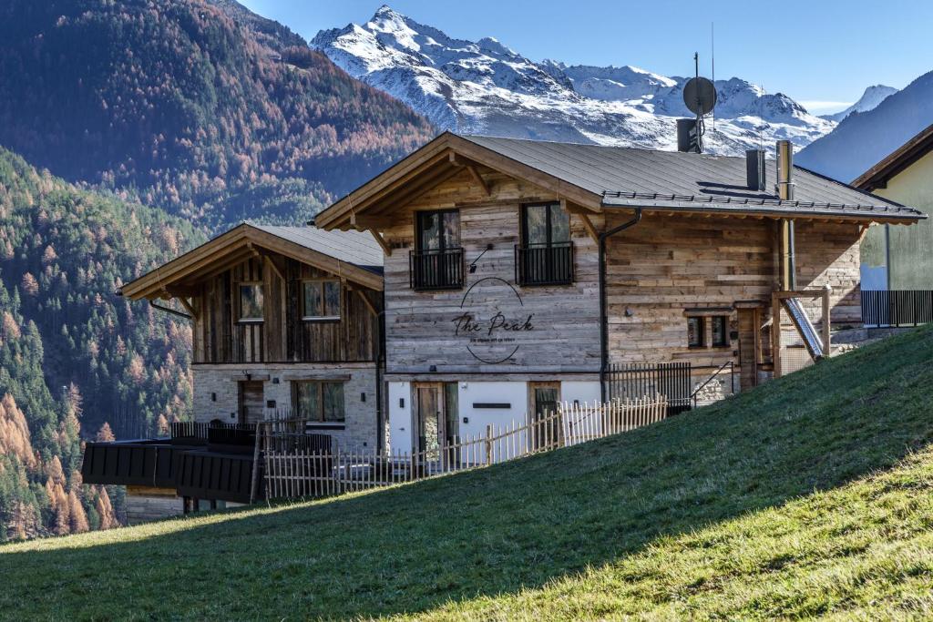 ein Haus auf einem Hügel mit Bergen im Hintergrund in der Unterkunft Chalets - The Peak in Sölden