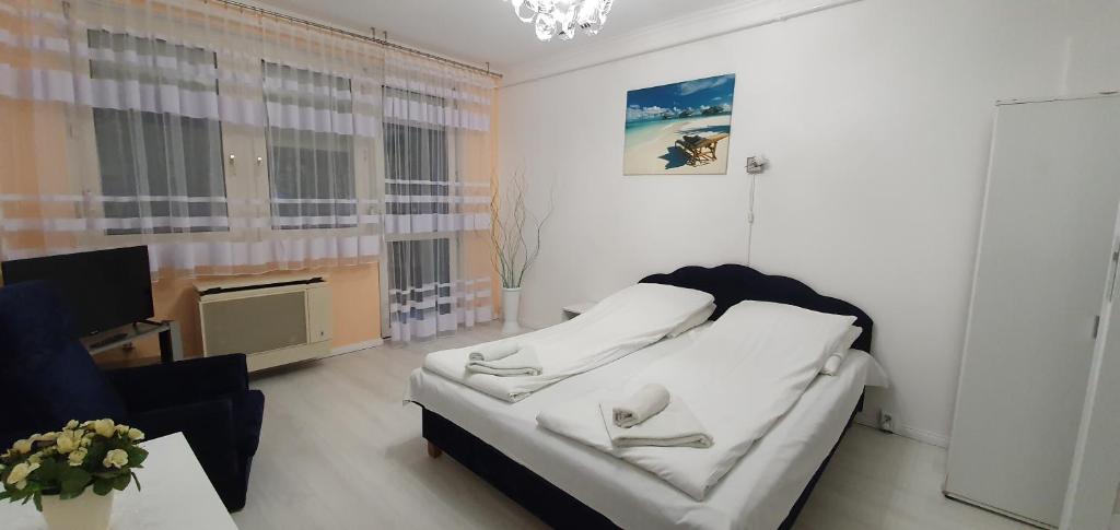 a living room with a white bed and a tv at Anna apartman in Szeged