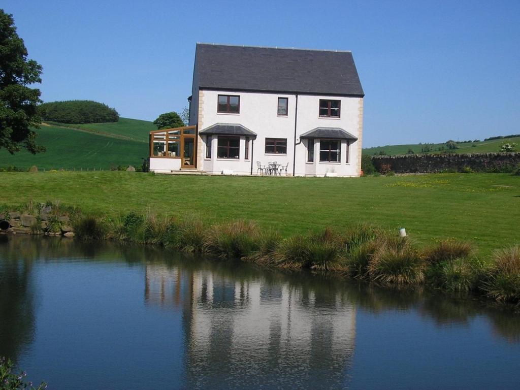 a house on a hill next to a body of water at Balhousie Farm Bed and Breakfast in Kirkton of Largo