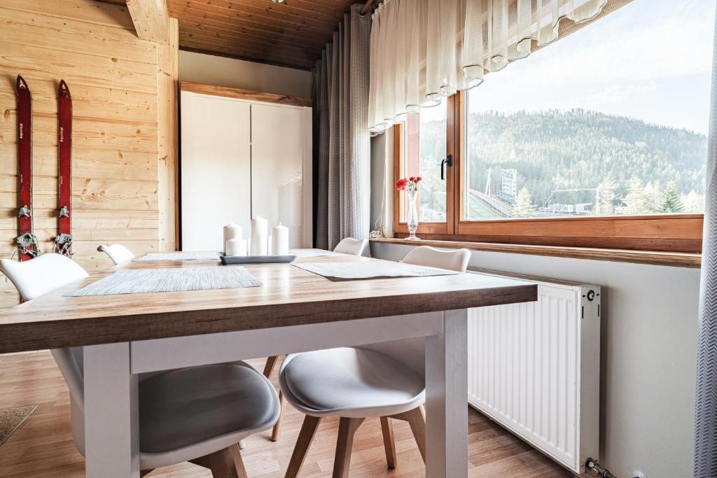 a dining room with a table and chairs and a window at apartamenty bogówka 11 in Zakopane