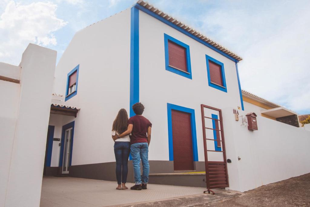 Un uomo e una donna in piedi davanti a una casa di Casa do Pequeno Dragoeiro ad Angra do Heroísmo