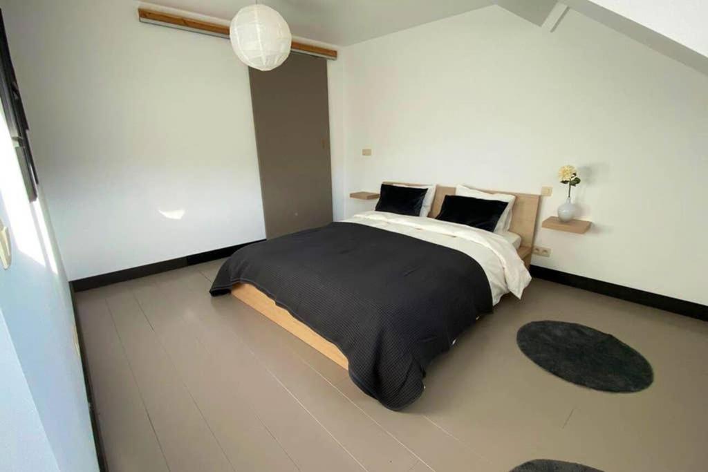 a bedroom with a large bed with black sheets and pillows at À deux PATENIER de Dinant in Dinant