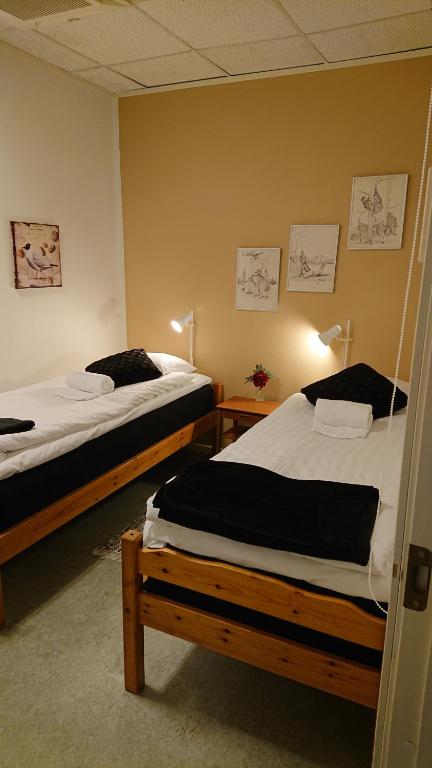 two beds in a room with two tables and two beds at Hvilan V-hem Norrtälje AB in Norrtälje