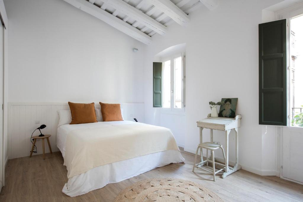 um quarto branco com uma cama e um banco em CASA FILOMENA em Barcelona