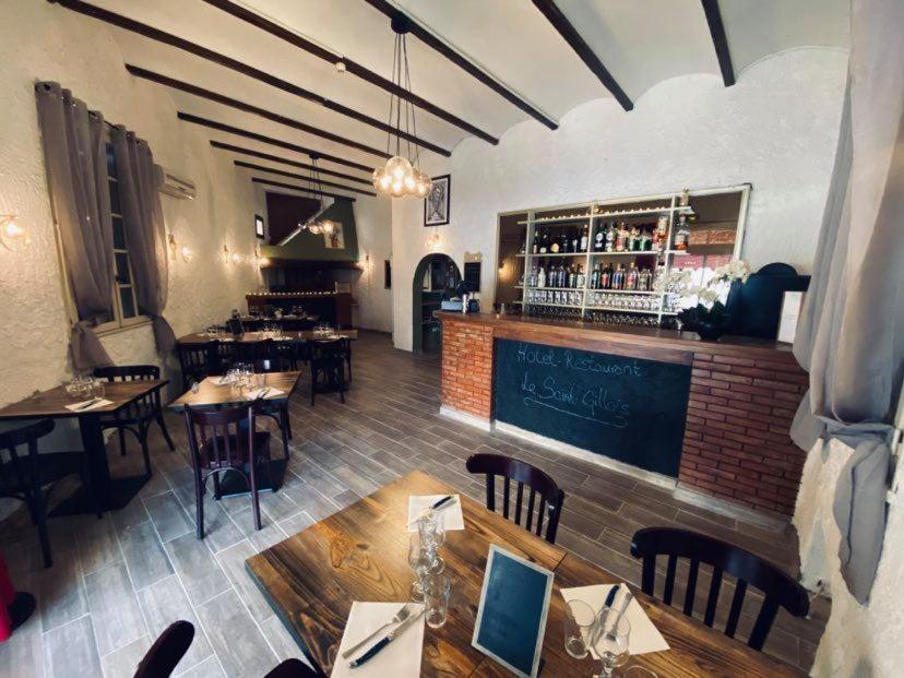 einen Blick über ein Restaurant mit Tischen und einer Bar in der Unterkunft Hôtel Restaurant Le Saint Gillois in Saint-Gilles