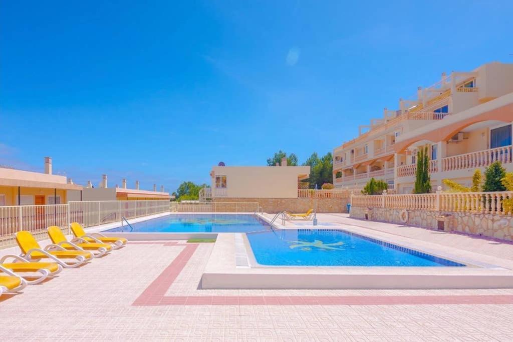 una piscina con tumbonas amarillas junto a un edificio en Casa Pitufo Calpe, bright duplex - see & mountain view, en Calpe