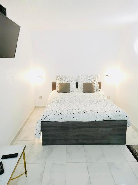 une chambre avec un grand lit dans une pièce blanche dans l'établissement Agréable studio à proximité de Paris et Henri Mondor, à Créteil