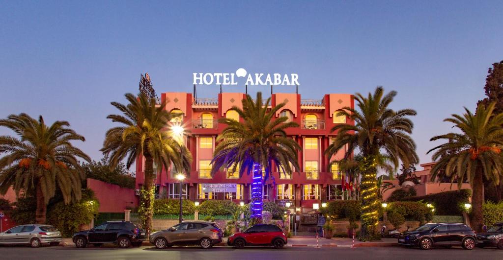 Hotel Akabar في مراكش: فندق kbar فيه سيارات متوقفة أمامه