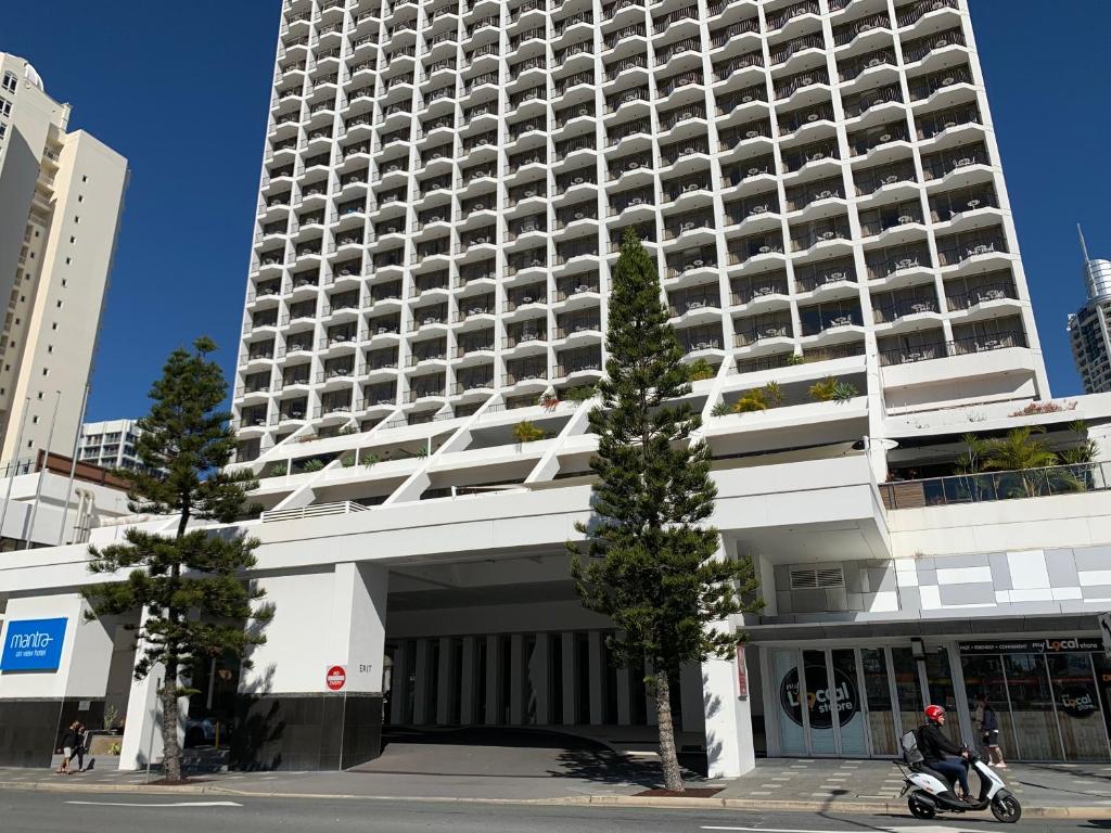 a man riding a scooter in front of a large building at High Floor Ocean View at Surfers Paradise - Hotel Studio in Gold Coast