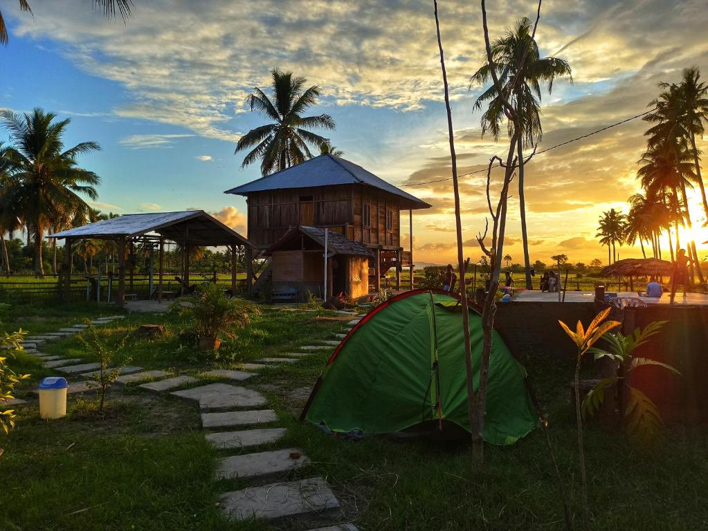 a tent in the grass in front of a building at Sunset Homestay by Harry & Mimin in Telaga