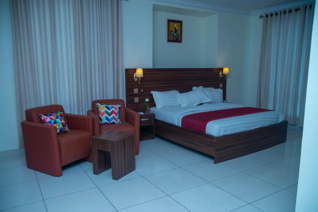 Posh Hotel and Suites Victoria Island في لاغوس: غرفه فندقيه بسرير وكرسي