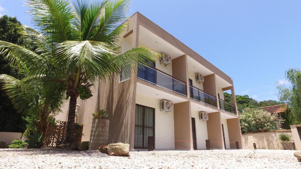 a building with a palm tree in front of it at Residencial Zé Buscapé in Bombinhas