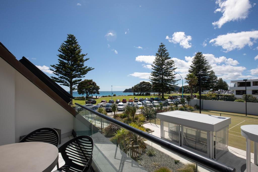 a balcony with tables and chairs and a view of a parking lot at Ocean Eleven Deluxe in Mount Maunganui