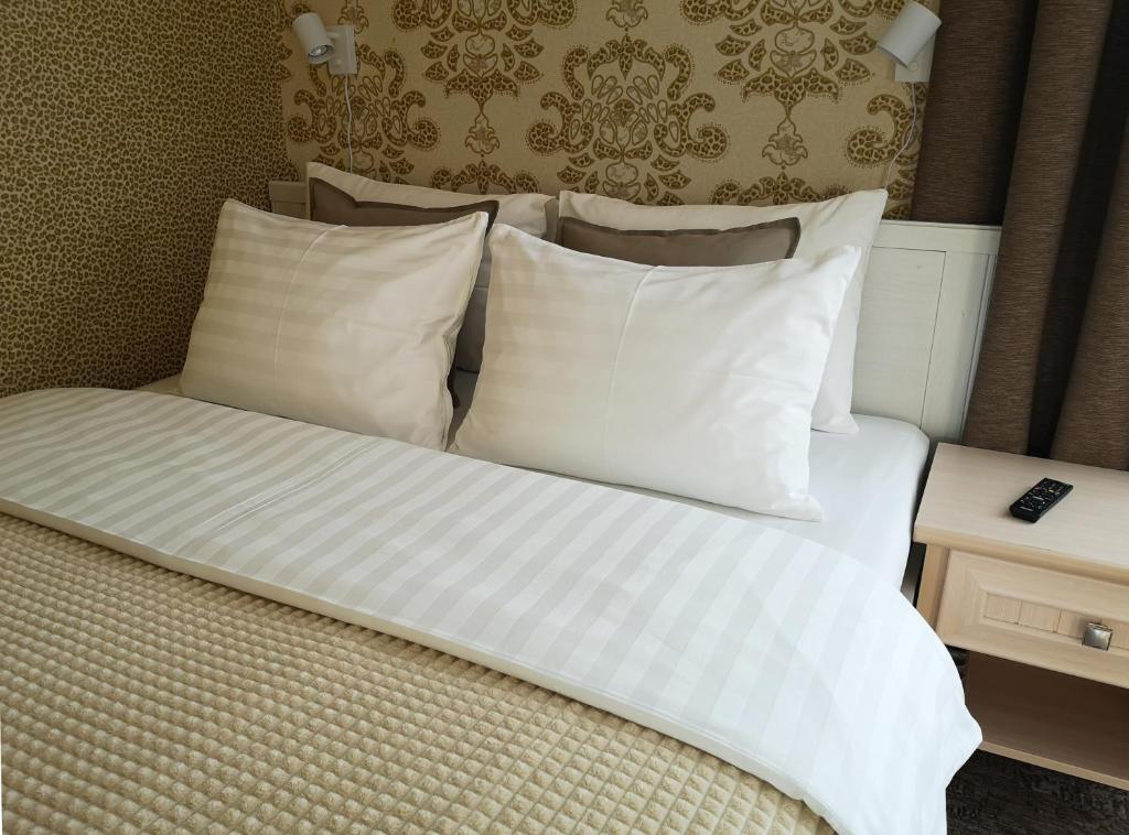 a bed with white sheets and pillows in a room at Apartment Like Your Home in Petropavlovsk-Kamchatskiy