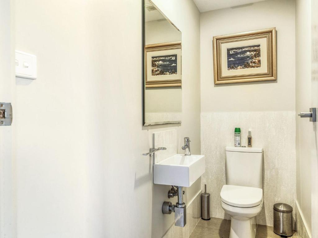 a white bathroom with a toilet and a sink at Riverleigh, Gerroa in Gerroa