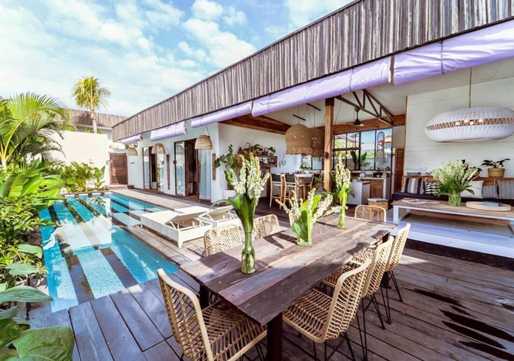 克羅柏坎的住宿－Villa Ubuntu by Optimum Bali Villas，一个带木桌和椅子的庭院和一个游泳池