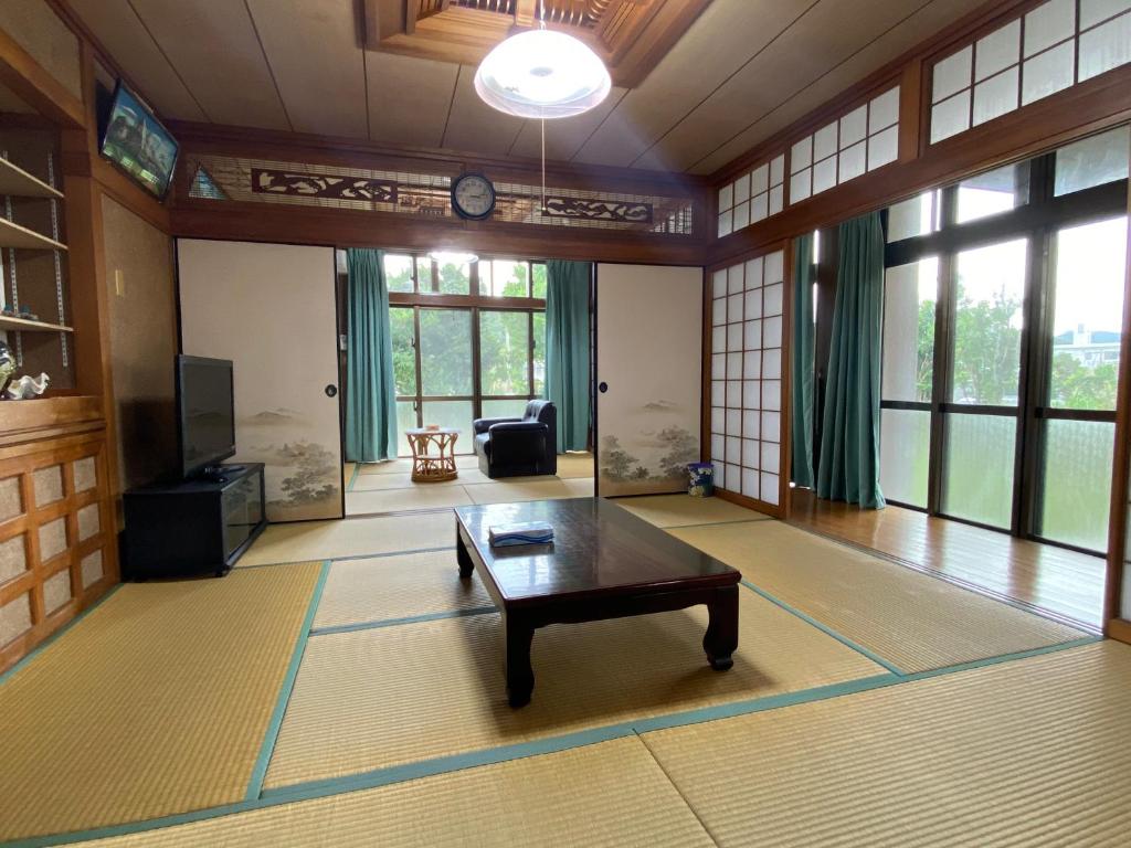 ein Wohnzimmer mit einem Couchtisch in einem Zimmer mit Fenstern in der Unterkunft てぃだかんかん Tida-kan-kan -SEVEN HOTELS & Resorts- in Motobu