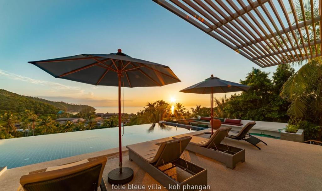 un patio avec chaises et parasols à côté d'une piscine dans l'établissement Folie Bleue Villa, à Mae Haad