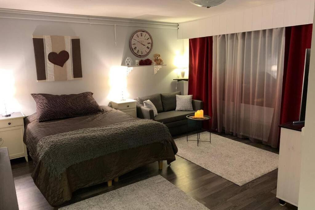 1 dormitorio con cama, sofá y reloj en 44m2 yksiö Joensuu, en Joensuu