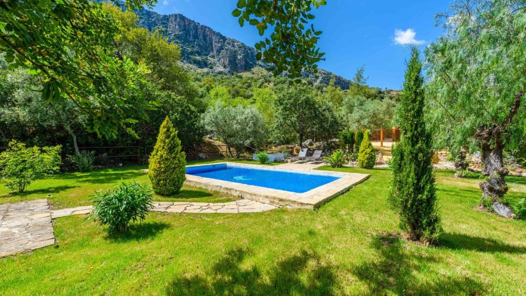 una piscina in un cortile con alberi e montagne di Casa El Rancho Montecorto by Ruralidays a Montecorto