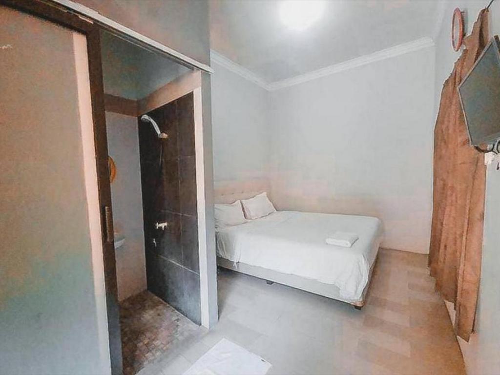 Cette petite chambre comprend un lit et une douche. dans l'établissement Safaraz Garden near Galaxy Bekasi Mitra RedDoorz, à Bekasi