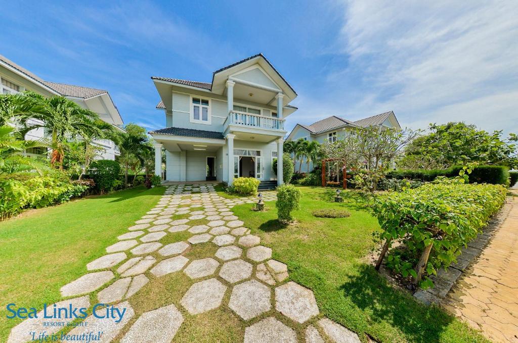 a house with a stone walkway in front of a yard at Sea Links Villa Resort & Golf in Mui Ne