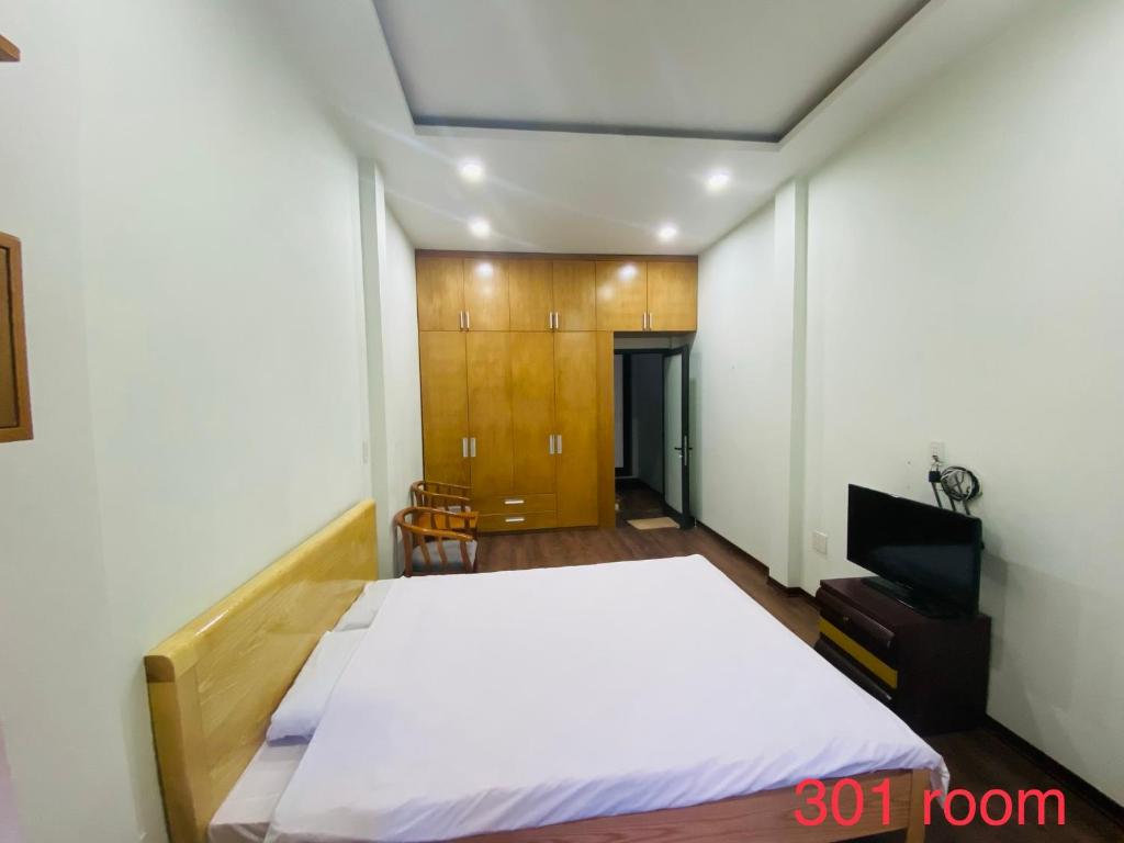 una camera con un grande letto bianco e una TV di Haiphong Backpacker Hostel a Hai Phong