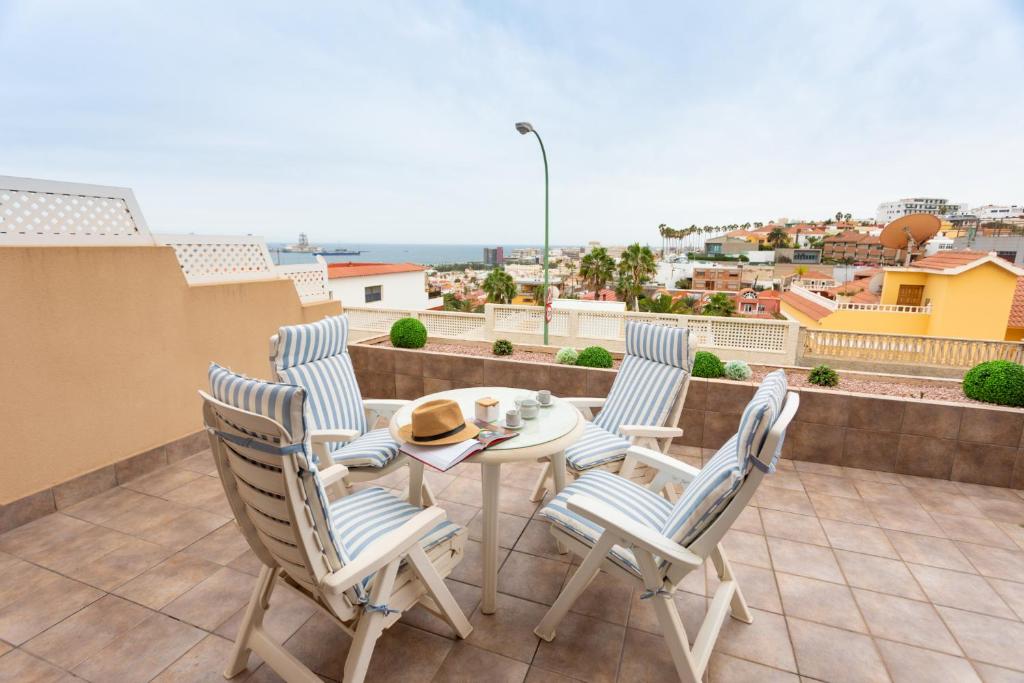 un patio con 4 sillas y una mesa en el balcón en La Cornisa Vivac House, en Las Palmas de Gran Canaria
