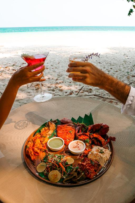 two people sitting at a table with a plate of food at Munjoh Ocean Resort - Private Beachfront Luxury Retreat in Havelock in Havelock Island