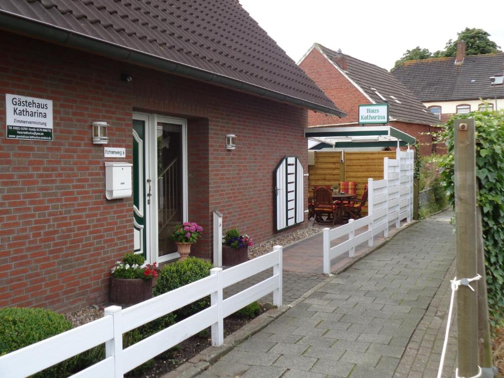 une maison en briques avec une clôture blanche et une allée. dans l'établissement Bastan - Haus Katharina, à Emden