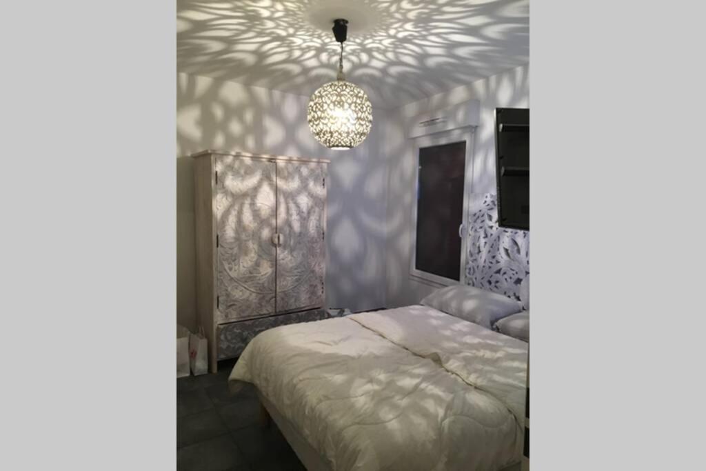 een slaapkamer met een bed en een kroonluchter bij Le Gallienice au cœur de la ville in Nice