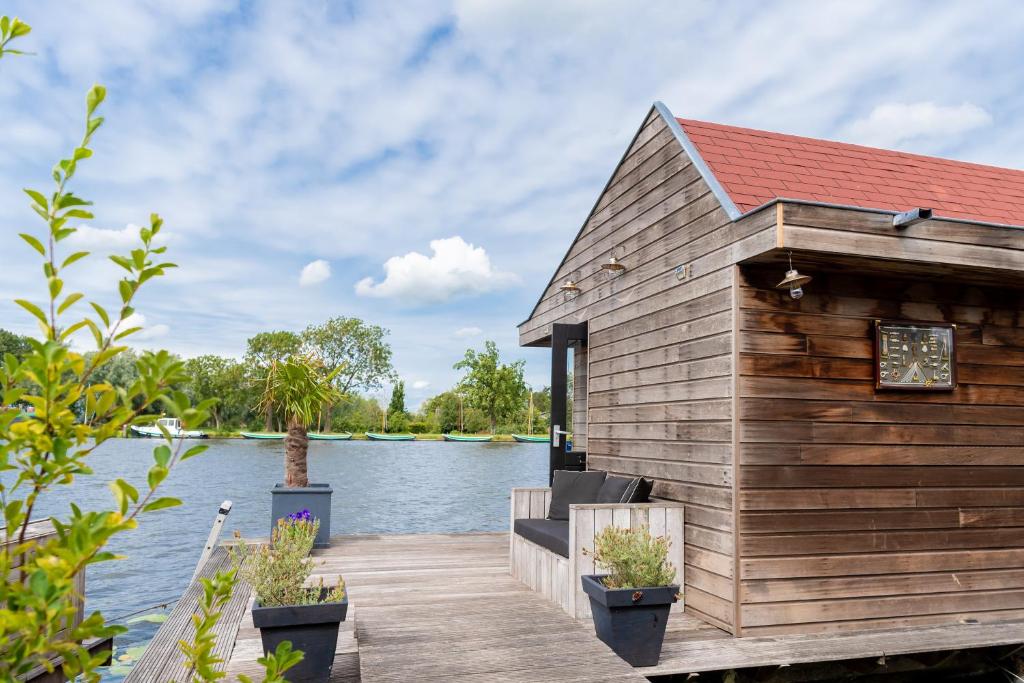 uma casa de madeira sobre uma doca sobre um corpo de água em Aangenaam op de Rijn, woonboot, inclusief privé sauna em Alphen aan den Rijn