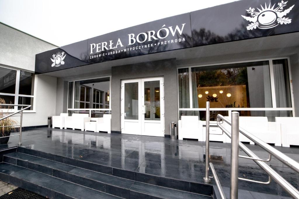 un front de magasin avec bancs blancs devant un bâtiment dans l'établissement Ośrodek Wypoczynkowo-Rehabilitacyjny Perła Borów, à Tleń
