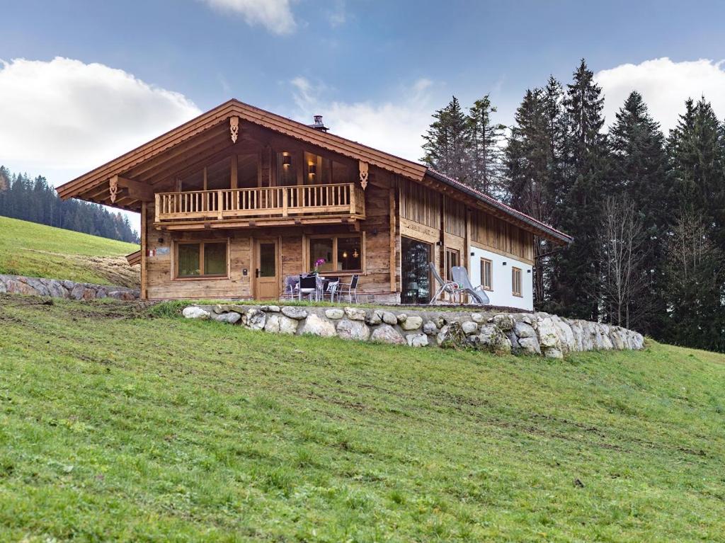 una cabaña de madera en una colina con un campo verde en Panorama Lodge, en Walchsee