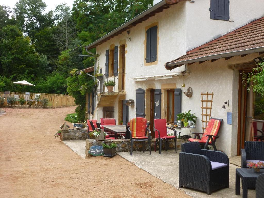un patio con sillas rojas y una mesa frente a una casa en la Bergerie du Bois Joannin 1497 route des fleuriats, en Iguerande