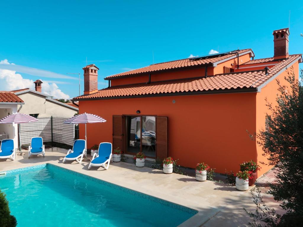 a house with a swimming pool with chairs and umbrellas at Holiday Home Starci - LBN406 by Interhome in Labin
