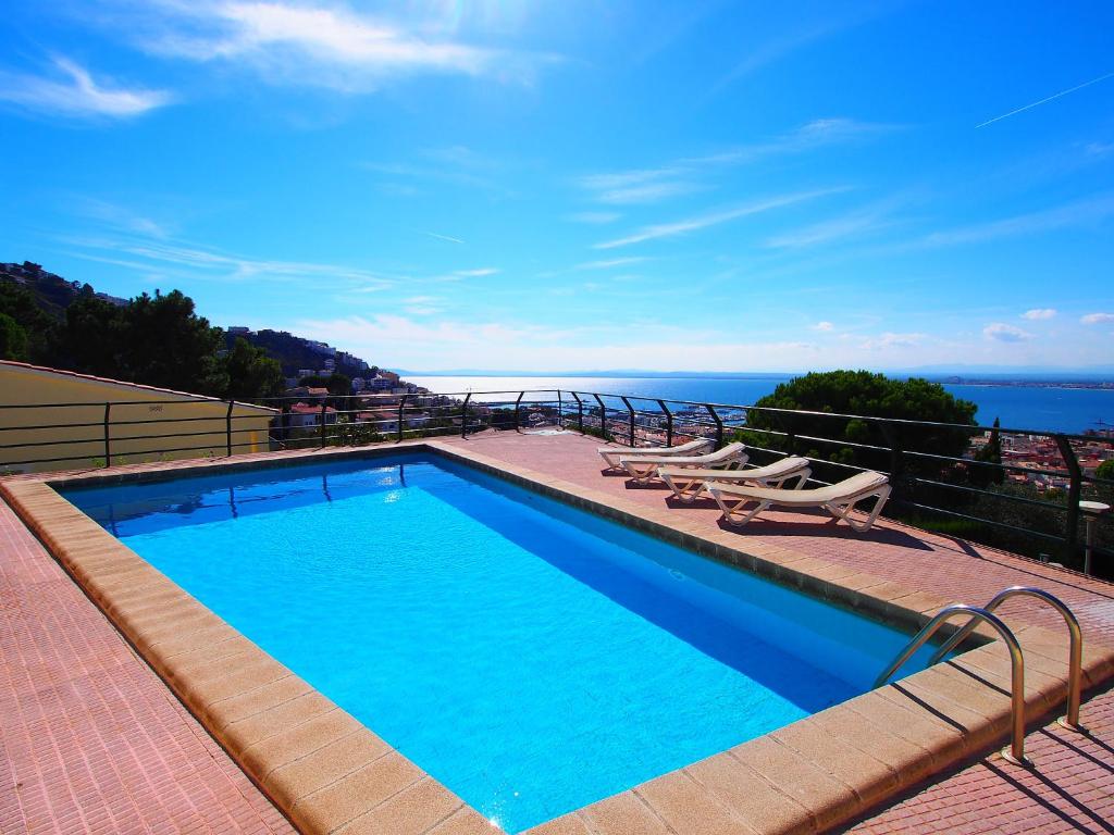 a swimming pool with two lounge chairs and the ocean at Apartment Las Alondras-2 by Interhome in Roses